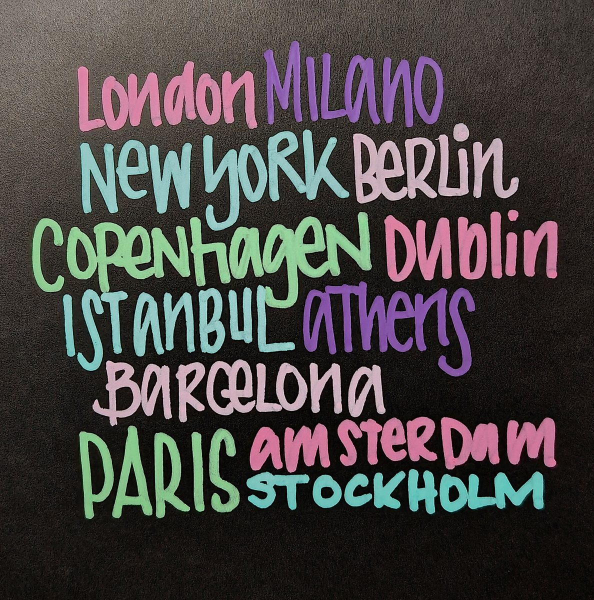 Colorful hand-lettered city names on a dark surface