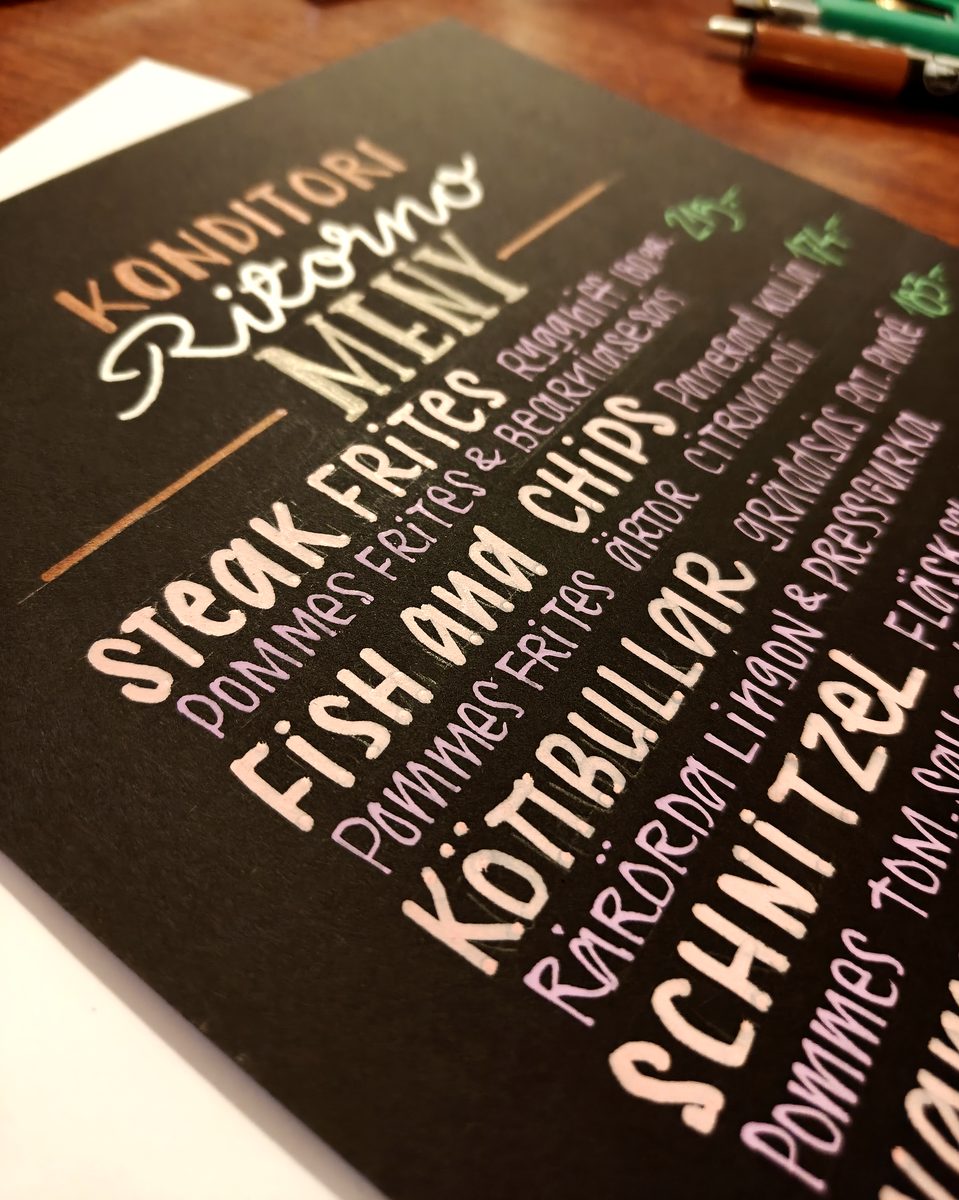 Angled close-up of a hand-lettered restaurant menu
